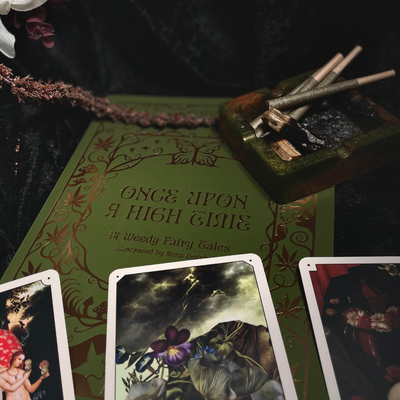 Fairy tale oracle card deck with illustrated cards, ashtray, and rolling papers on display
